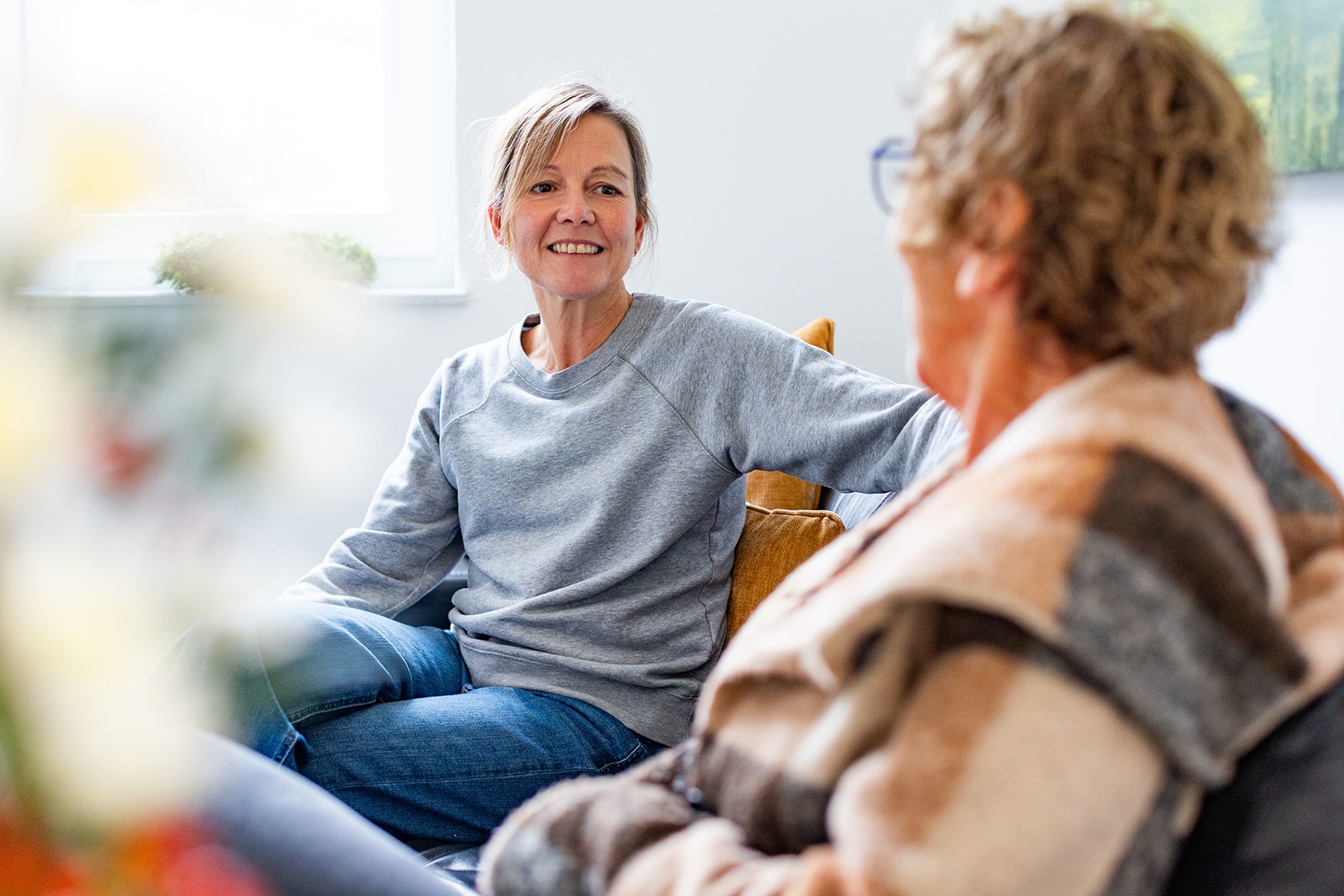 Pflegekraft besucht eine ältere Person zu Hause, bietet einfühlsame Unterstützung im familiären Umfeld.