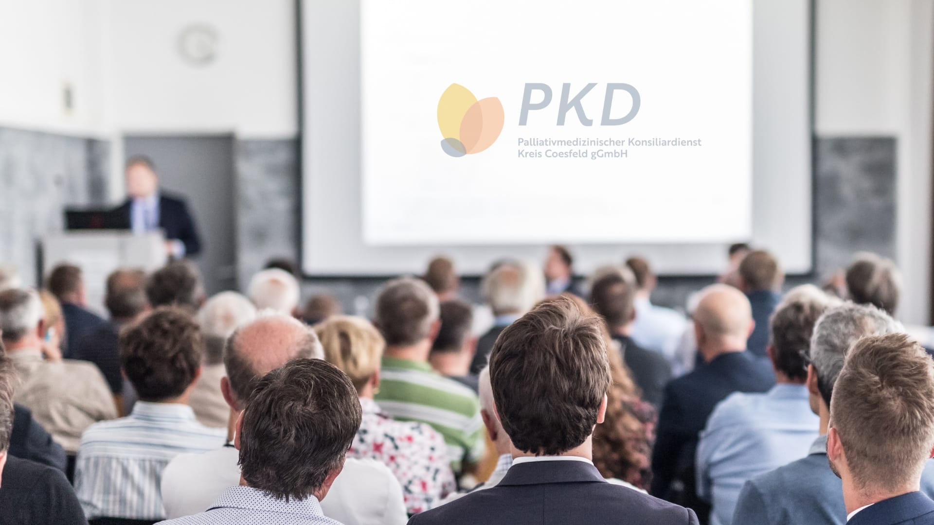 Vortrag vor Publikum mit Präsentationsfolie des Palliativmedizinischen Konsiliardienstes